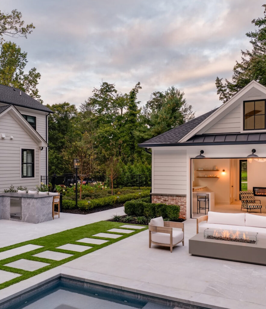 Outdoor kitchen, pool house, and fire-table seating around the pool