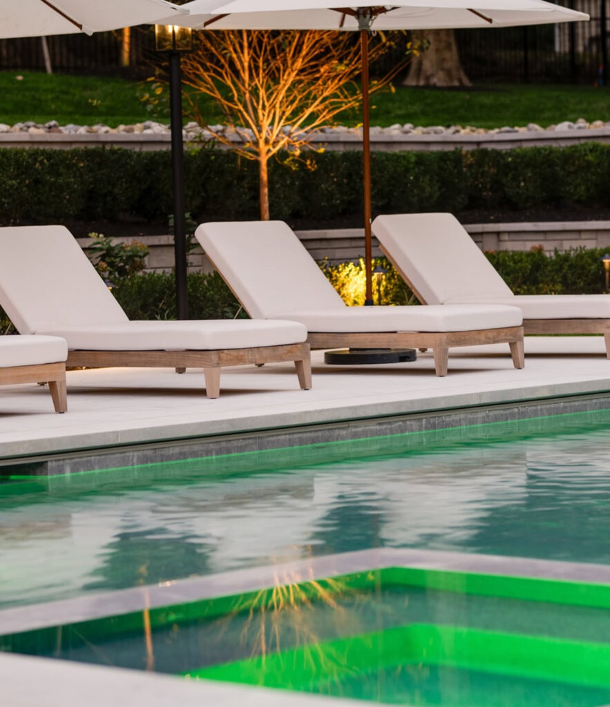 Chaise lounges beside the pool and green-lit spa