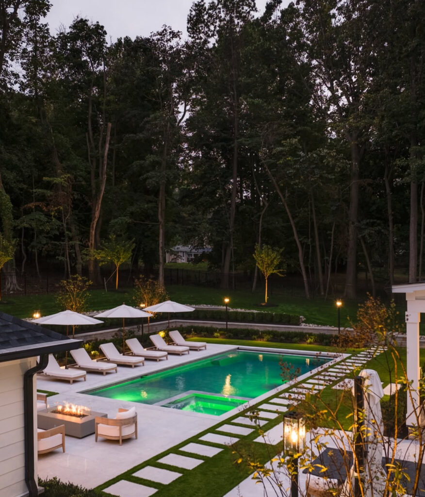 Elevated view of the illuminated pool, spa, and surrounding paths