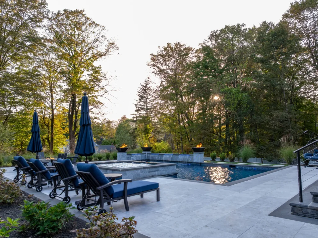 Backyard pool with raised spa, fire bowls, waterfalls, and blue lounge chairs