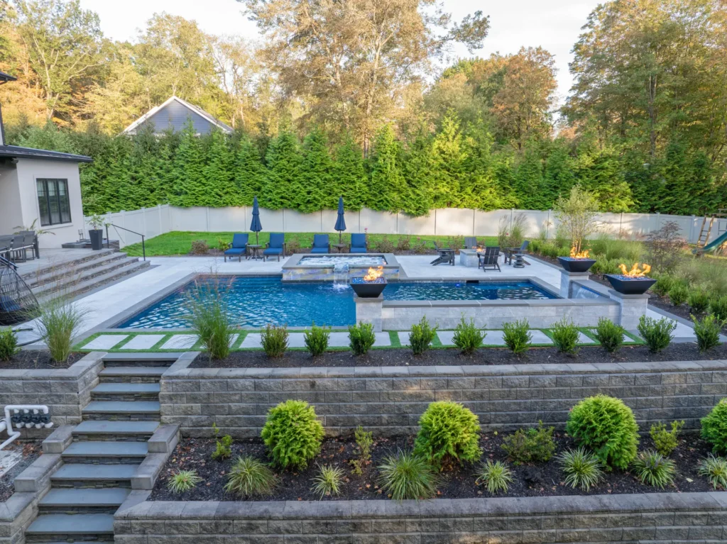 Terraced backyard pool with raised spa, fire bowls, waterfalls, and landscaping