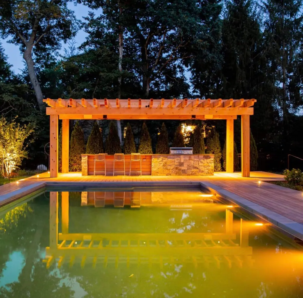 Illuminated pergola and bar reflected in the pool at night